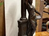 a bronze statue of a woman holding a lamp post