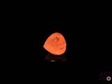 un gros plan sur un caillou qui brille dans l'obscurité, avec la lune en arrière-plan