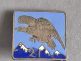 une image représentant une broche en forme d'aigle argenté et bleu, avec des montagnes en arrière-plan