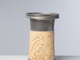 un petit vase orné d'un motif, posé sur une table