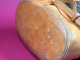 a brown bag with a brown handle on a pink surface