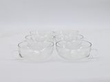 four clear glass coffee cups sitting on top of a white surface