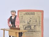 a toy man standing in front of a desk with a newspaper