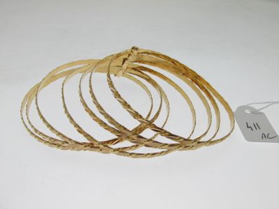plusieurs bracelets en or posés sur un fond blanc, accompagnés d'une étiquette de prix