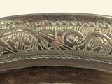 a silver plate with a design on it on a table