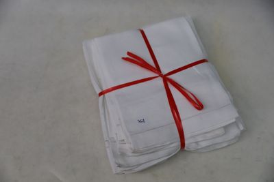 several folded white napkins tied with red ribbon on a table