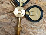 a close up of a brass colored propanent on a wooden surface