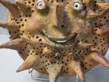 a clay sculpture of a sun face on a stand