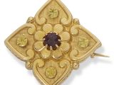 un gros plan sur une broche en or sertie d'une pierre violette