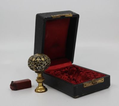 une petite boîte noire doublée de velours rouge et contenant une boule d'or