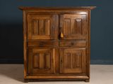 an old wooden cabinet with three doors and a drawer underneath it