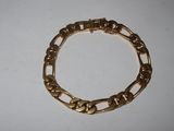 a close up of a gold bracelet on a white surface
