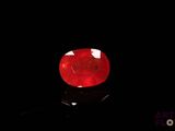 a close up of a red ruby stone on a black surface