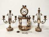 trois bougies et une horloge posées sur une table