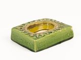 a small green candle holder on a white surface