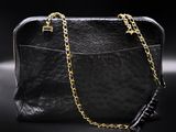 a black purse with gold chains on a black background