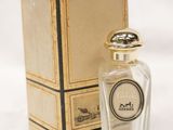 an old bottle of perfume sitting next to a box on a white surface