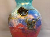 a colorful vase sitting on a white surface