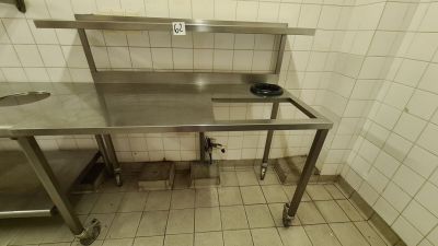 a stainless steel table in the middle of a tiled room