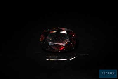 un diamant rouge sur une surface noire