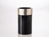 une image représentant un vase noir et argenté posé sur une surface blanche
