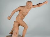statue of a man throwing a frisbee on a wooden base