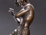 bronze statue of a young man holding a tennis racquet on a marble base