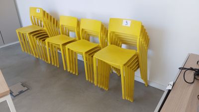 Plusieurs chaises jaunes sont alignées contre un mur dans une pièce