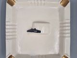 white porcelain ashtray with gold rims and a black top