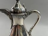 an antique silver coffee pot with a handle and a lid