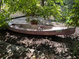 un canoë rose posé par terre sous un arbre