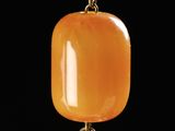 an image of a yellow jade pendant with a flower on a chain