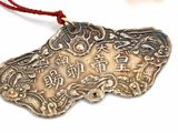 a silver pendant on a red string on a white surface
