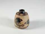 un petit vase avec un motif sur une surface blanche