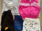 a pile of clothing that includes a jacket, shorts, and shoes