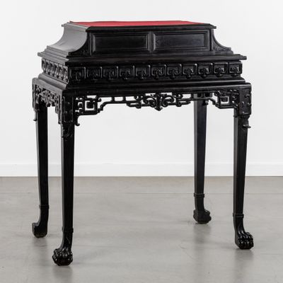 une image représentant une table noire sur laquelle est posé un coussin rouge