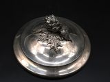 a silver plate with a flower on it on a black surface