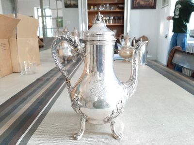 une théière en argent posée sur une table au milieu d'une pièce