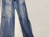 un pantalon en jean troué posé sur un lit dans une chambre