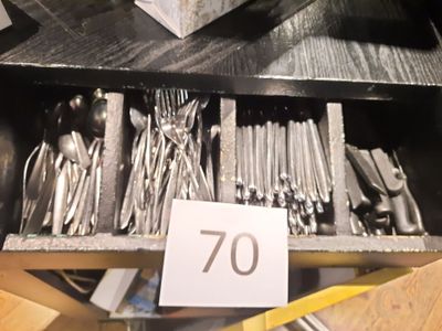 un tiroir rempli d'argenterie et d'ustensiles dans un magasin