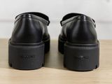 black leather shoes with black rubber soles on a wooden surface