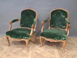 paire de fauteuils en velours vert avec des accoudoirs en bois sculpté