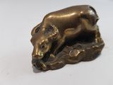 brass figurine of a bull resting on a rock