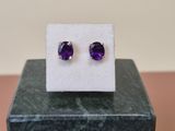 une paire de boucles d'oreilles en amethorate posées sur un bloc de marbre