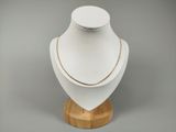 un gros plan d'un collier posé sur un support en bois, sur fond gris