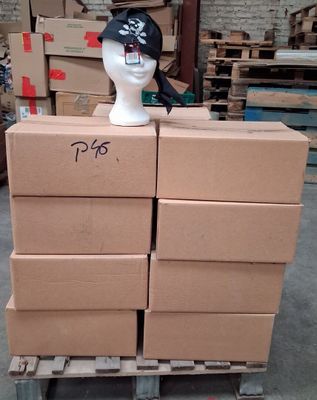 des cartons empilés sur une palette, surmontée d'un chapeau