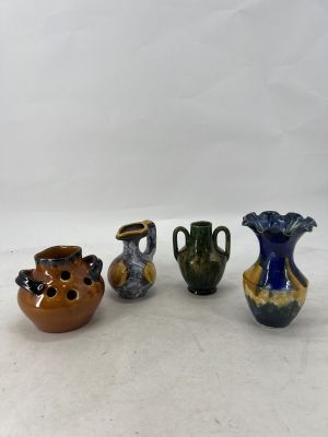 four different colored vases sitting on top of a white surface