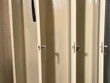 three lockers in a room with a toilet and a trash can