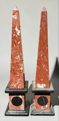 pair of red marble obelisks with black bases on stands