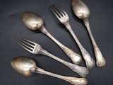 four silver spoons and a fork on a black surface